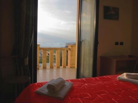 Camera di Casa Rosmini con la porta aperta verso il balcone e il mare